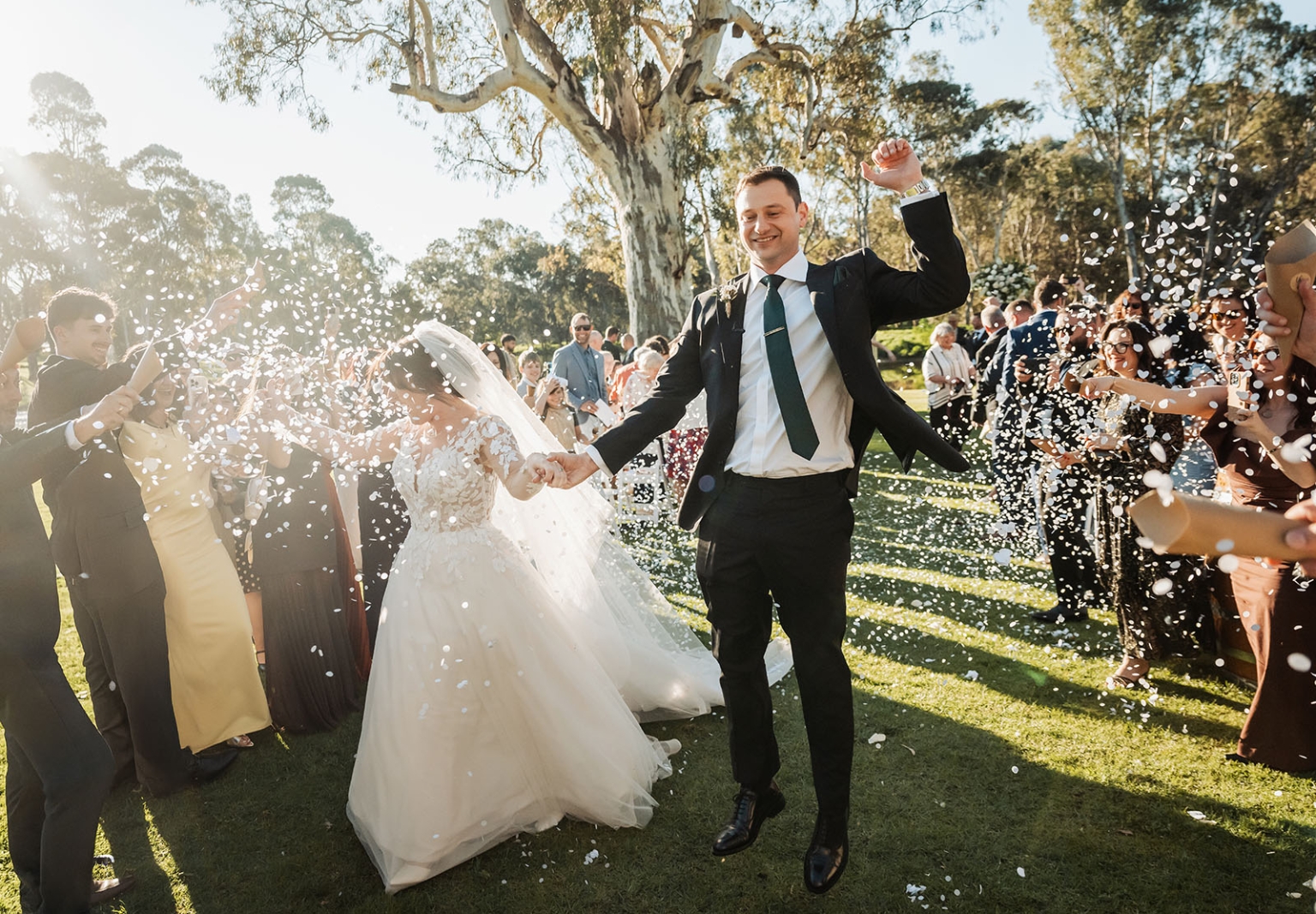 serafino winery wedding – maor & sasha 36 Newlyweds walk through a shower of white confetti thrown by wedding guests on a lawn at Serafino Winery.