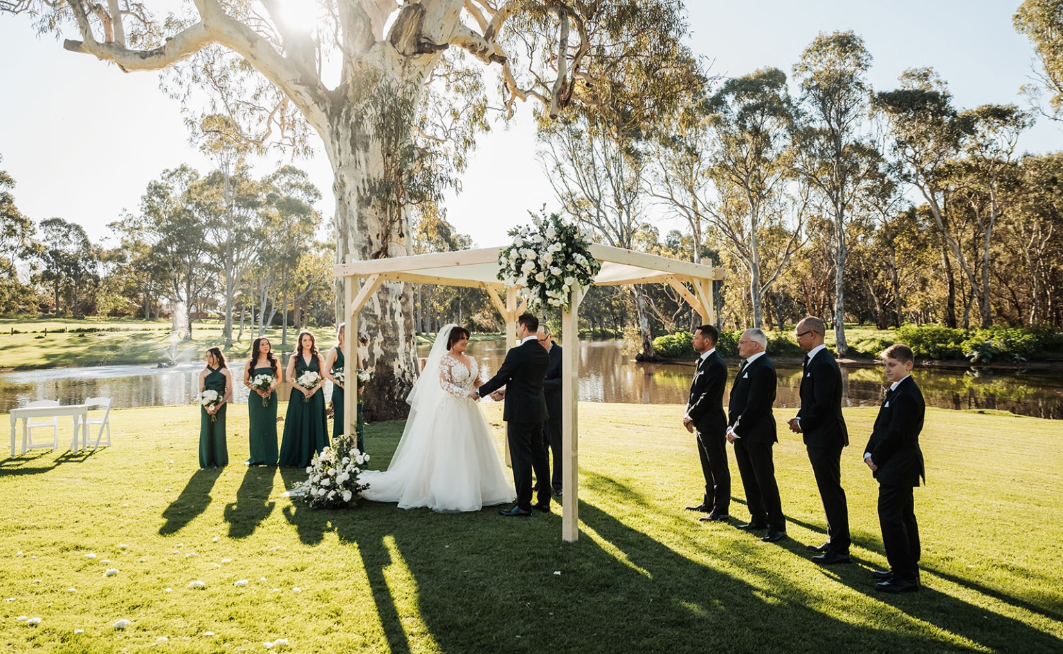 serafino winery wedding – maor & sasha 29 Bride and groom holding hands beneath a flowered timber arbour during their outdoor wedding ceremony at Serafino Winery