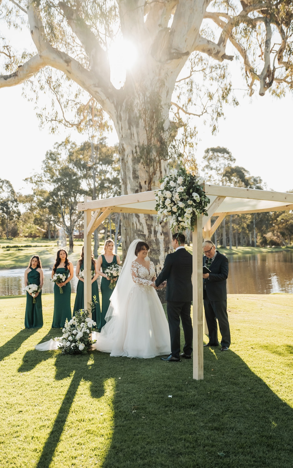 serafino winery wedding – maor & sasha 30 Bride and groom holding hands beneath a flowered timber arbour during their outdoor wedding ceremony at Serafino Winery