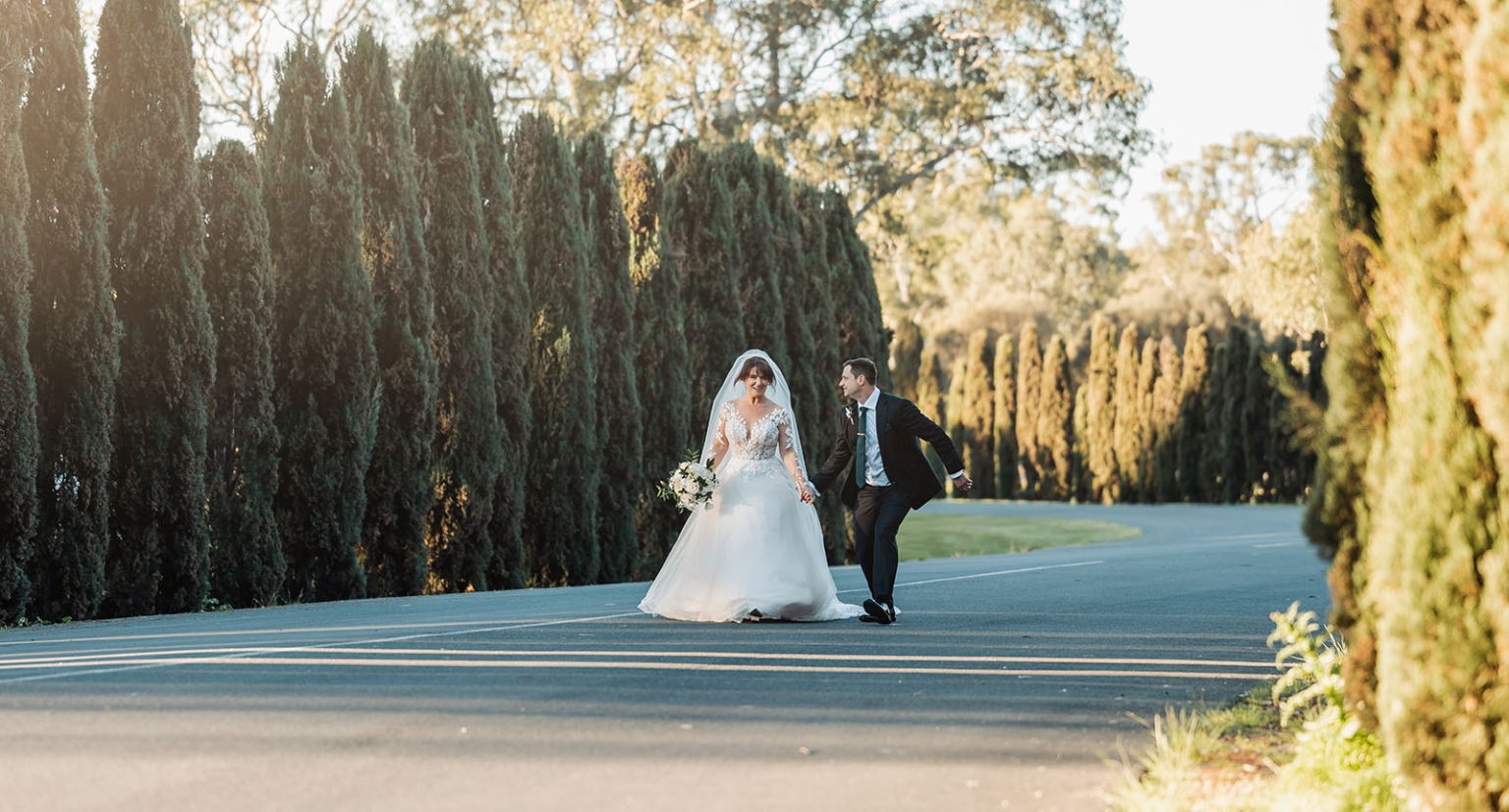 serafino winery wedding – maor & sasha 42 Bride and groom holding hands and walking between tall cypress hedges at Serafino Winery