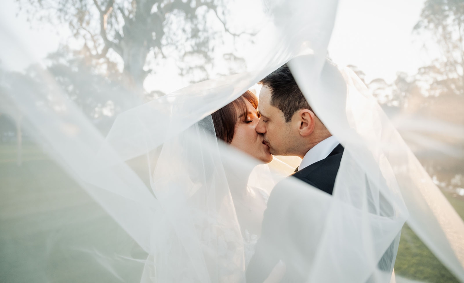 serafino winery wedding – maor & sasha 51 Bride and groom kissing beneath the bride’s flowing veil outdoors at Serafino Winery