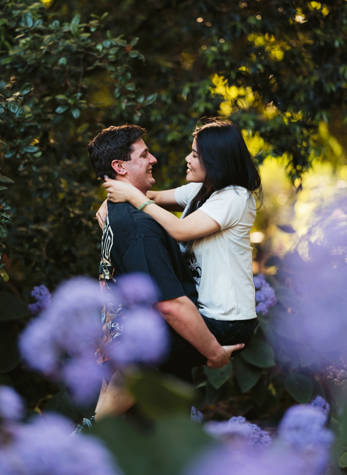 adelaide botanic gardens proposal – stewart & levi 14 Stewart holding Levi as they smile at each other among purple flowers at Adelaide Botanic Gardens