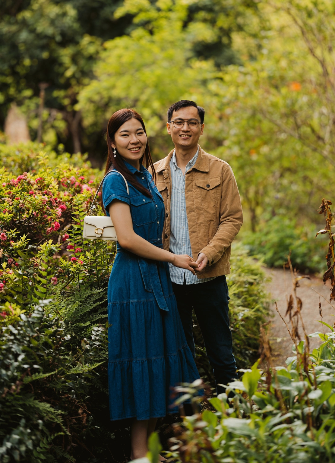 mt lofty botanic park proposal – watay & phouthun 14 Watay and Phouthun holding hands beside pink flowering shrubs in Mount Lofty Botanic Garden