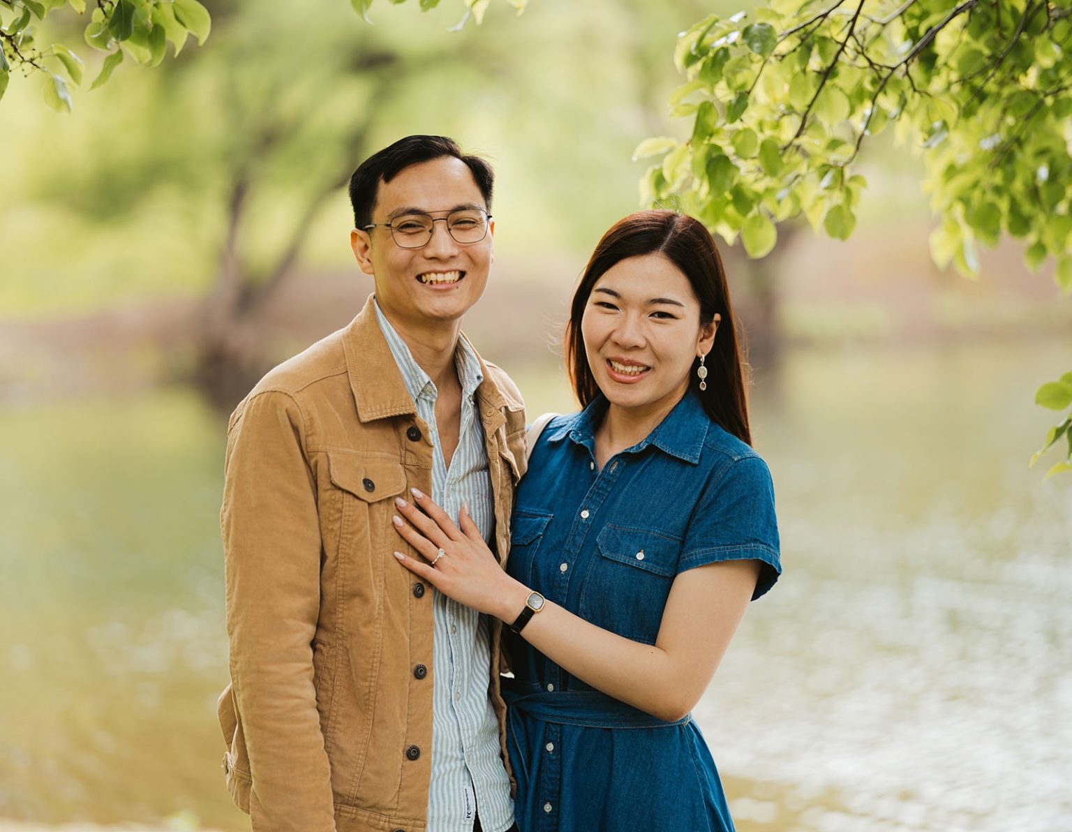 mt lofty botanic park proposal – watay & phouthun 8 Watay and Phouthun smiling together beneath leafy branches, with Phouthun's engagement ring visible on her hand