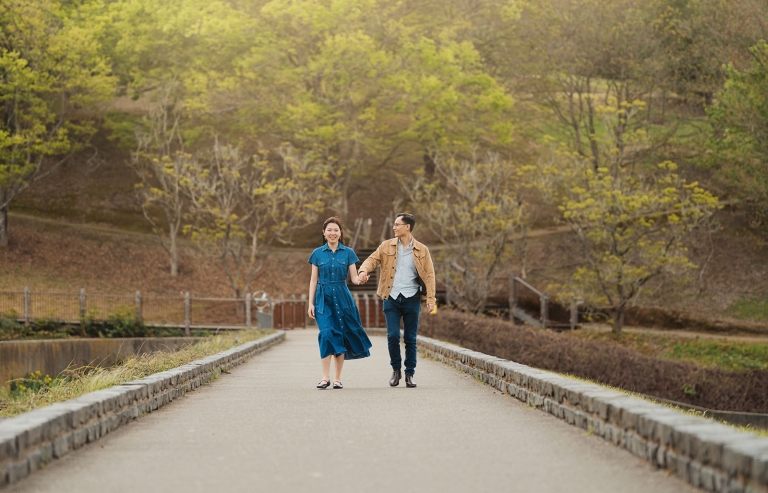 Watay and Phouthun holding hands as they walk along a stone-lined path at Mount Lofty Botanic Garden