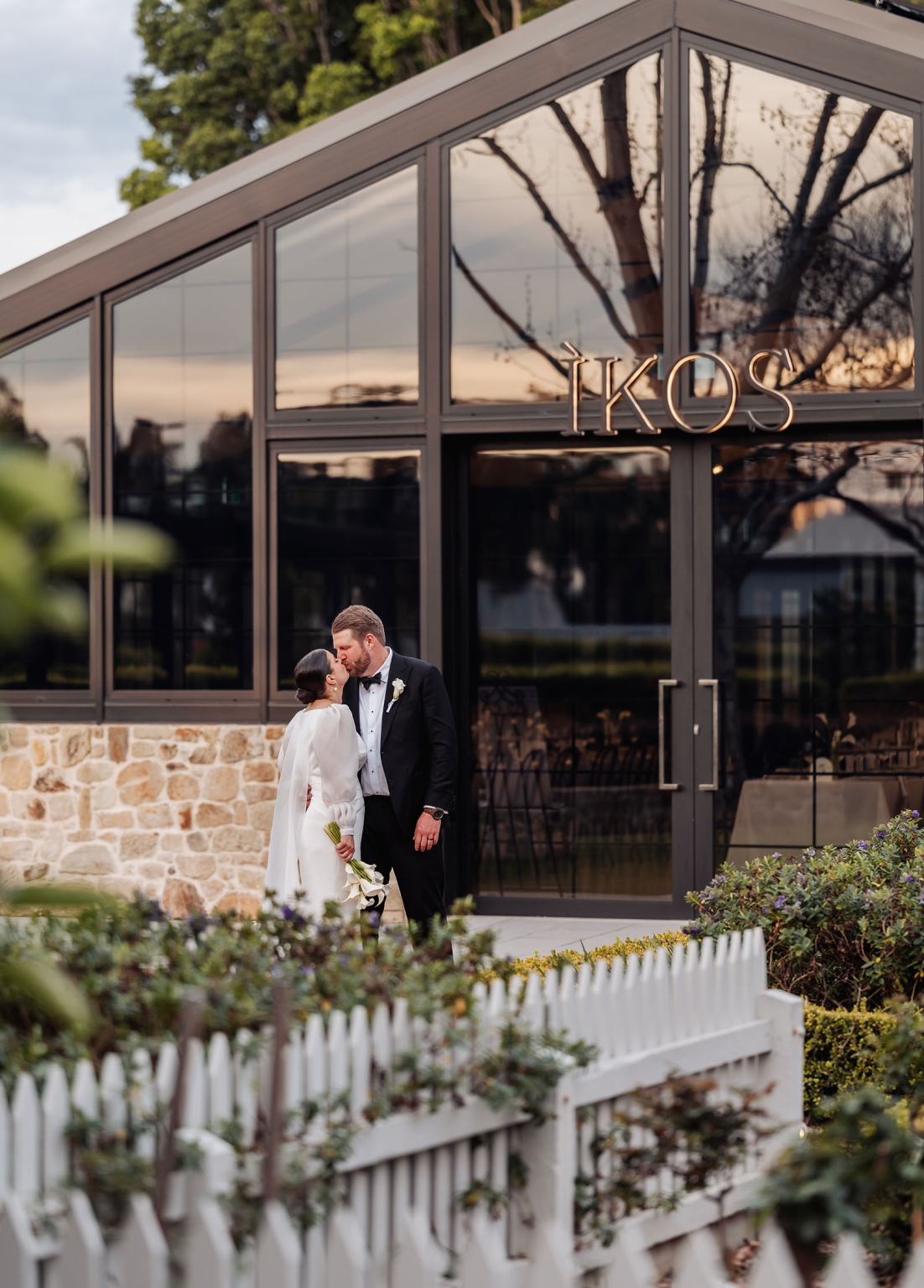 st joseph's chapel wedding – diana & michael 39 Newlyweds kissing outside the KOS building, with the bride holding a white bouquet