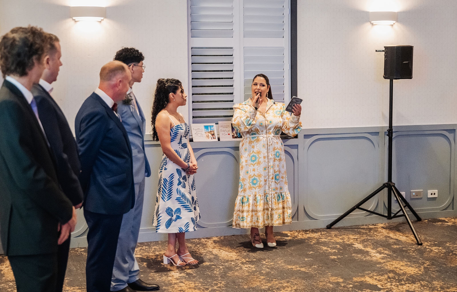 hotel royal wedding - brad & manuel 25 Wedding guest speaking into a microphone and holding a phone as guests listen in a reception room