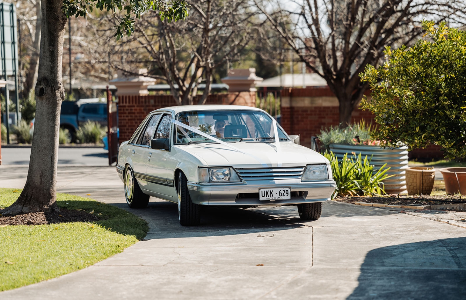 st joseph's chapel wedding – diana & michael 4 White vintage sedan decorated with wedding ribbons parked on a leafy driveway at St Joseph's Chapel, Kensington