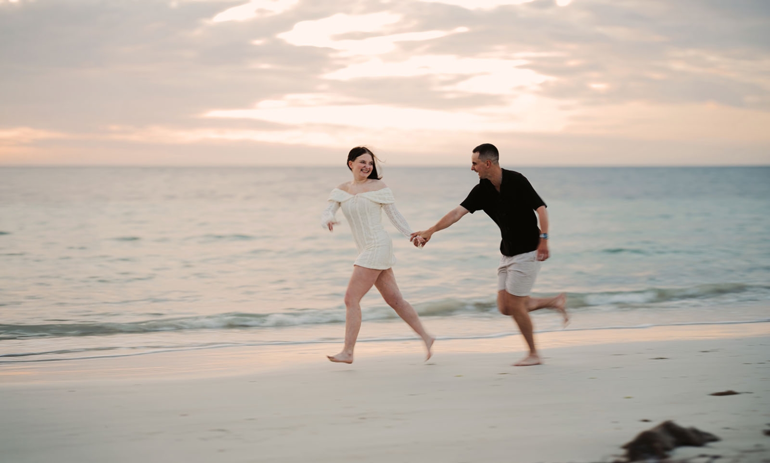 moonta's simms cove proposal – zoe & nathan 30 Zoe and Nathan holding hands as they run barefoot along Simms Cove beach at sunset