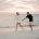 Zoe and Nathan holding hands as they run barefoot along Simms Cove beach at sunset