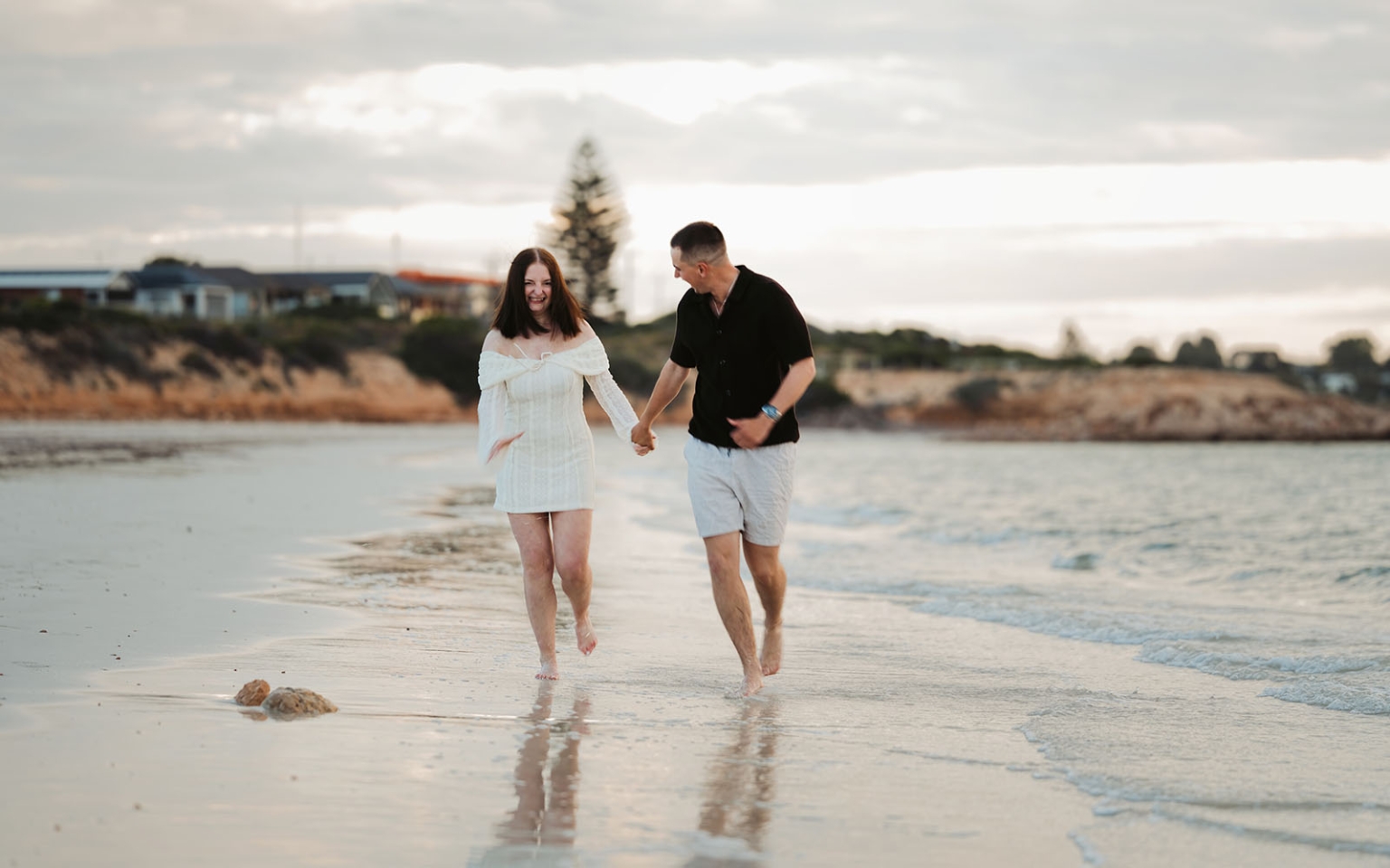 moonta's simms cove proposal – zoe & nathan 18 Zoe and Nathan holding hands while walking barefoot along the shoreline at Simms Cove, Moonta