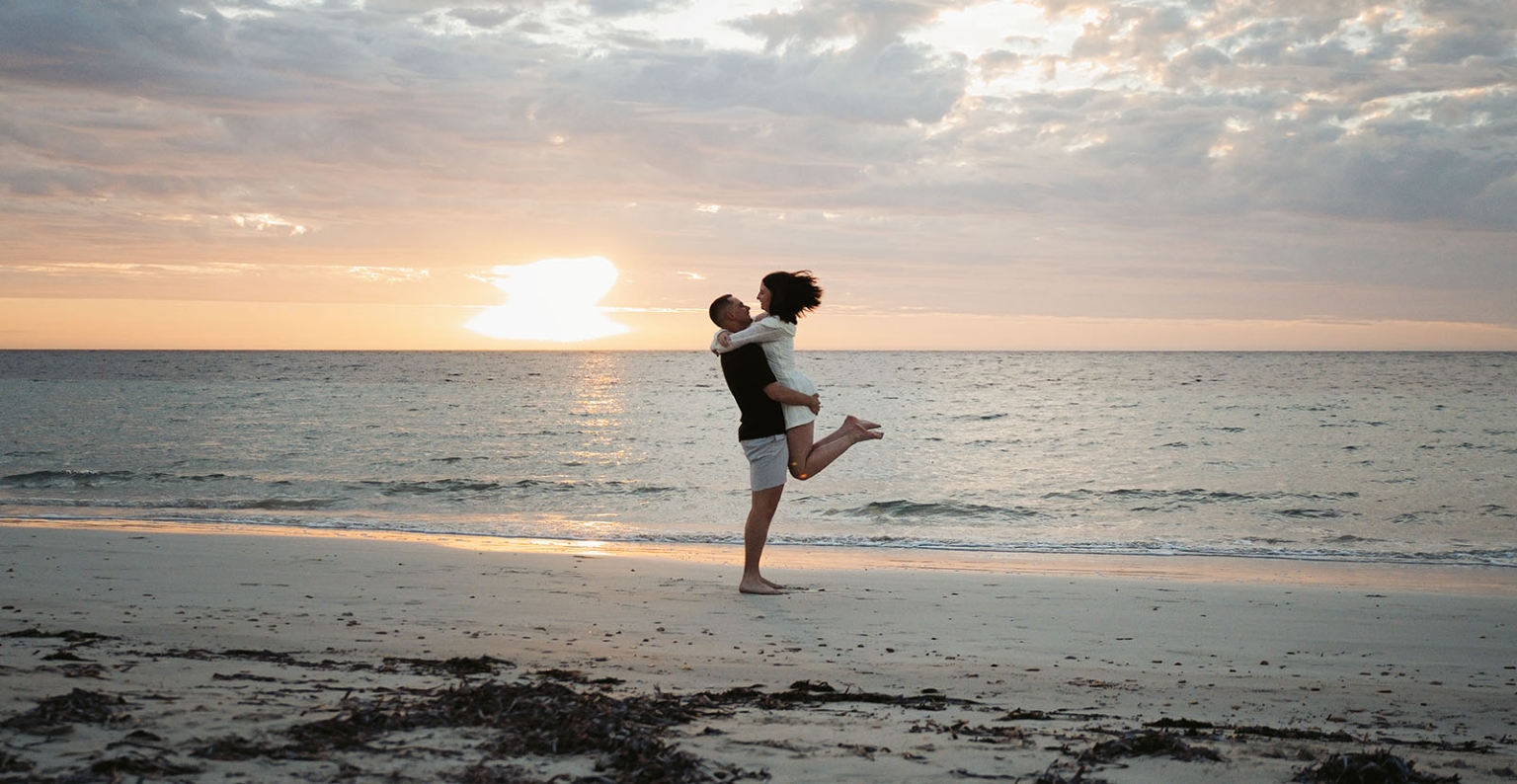 moonta's simms cove proposal – zoe & nathan 31 Nathan lifts Zoe as they embrace on Simms Cove beach at sunset in Moonta